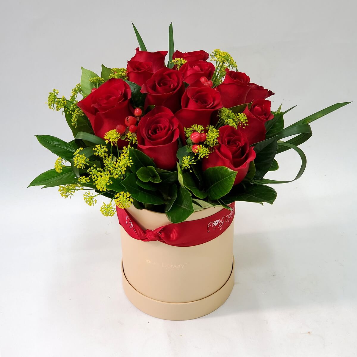 A dozen red roses accented with red hypericum berries and lush greens, styled in a soft cream hat box – 十二朵紅玫瑰配紅豆與青綠葉材，擺設於溫潤米白圓盒中，典雅浪漫