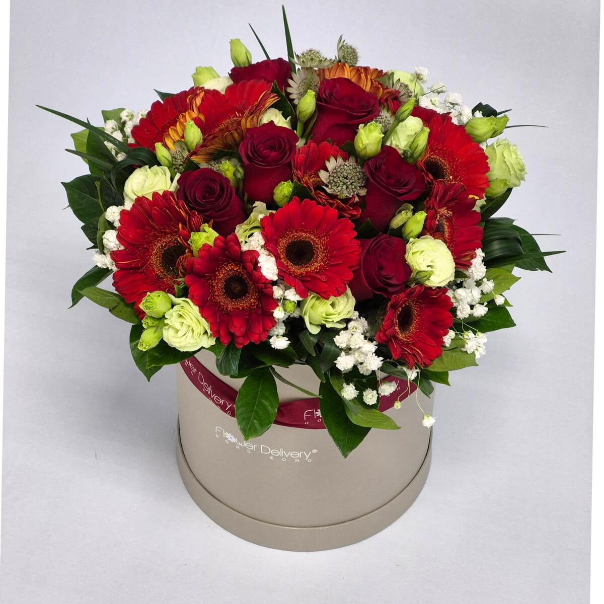 Real photo of round hatbox arrangement with red roses, red gerbera daisies and foliage - 紅玫瑰配紅色非洲菊及綠葉圓形帽盒花藝設計