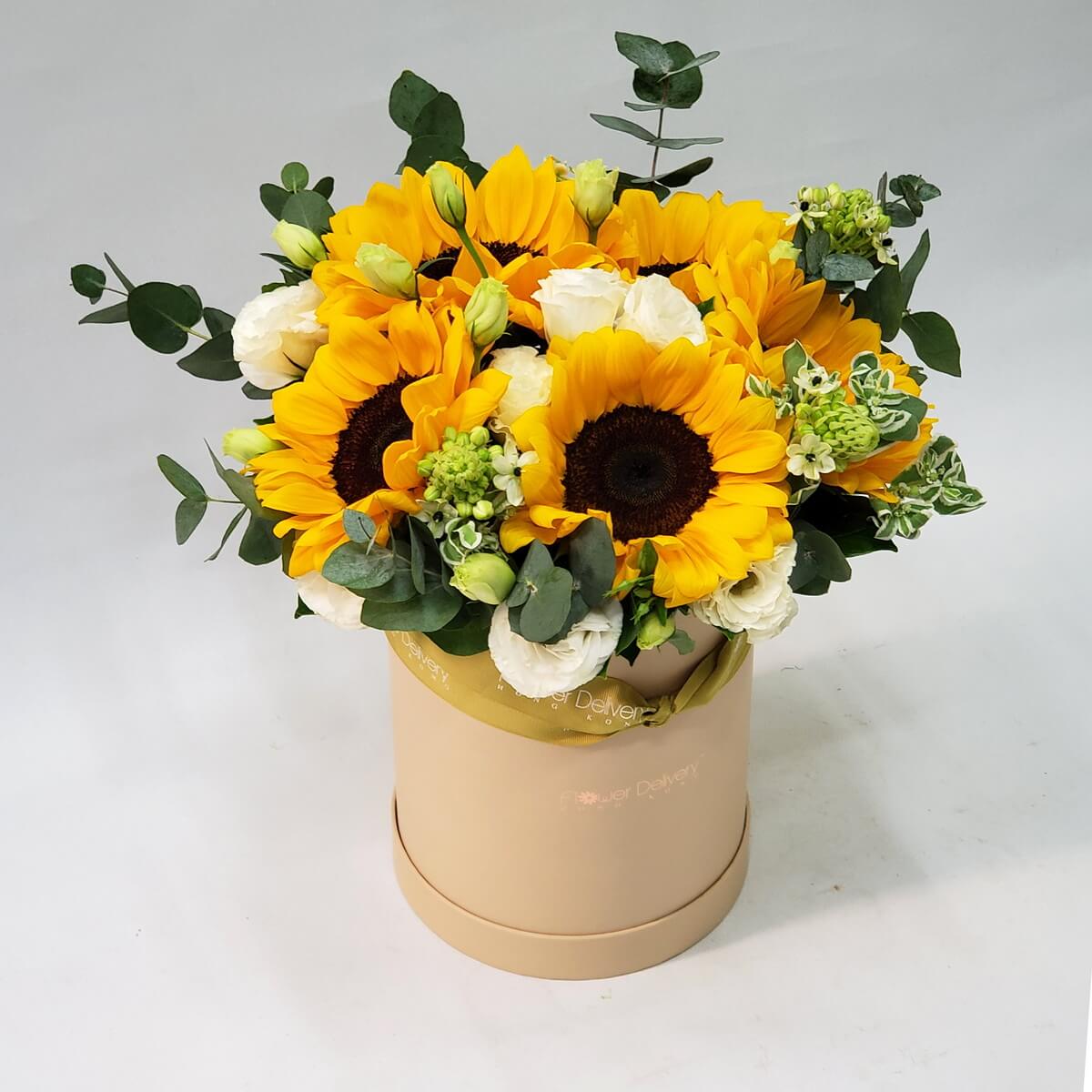 Pink stargazer lilies surrounded by curled leaves and green filler accents, arranged in a soft cream round hat box – 粉紅星辰百合配螺旋葉與綠色襯材，設計於米白圓形帽盒中，色彩柔和