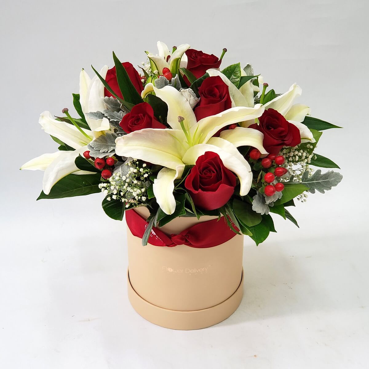 Elegant mix of white lilies, red roses, red berries, and baby's breath arranged in a cream round hat box – 白百合、紅玫瑰與紅色果實、滿天星混搭，裝飾於米白圓形帽盒內，綠葉襯托