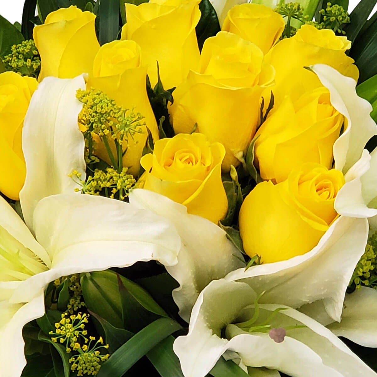 Detail view of a floral arrangement featuring yellow roses, white oriental lilies, and airy green fillers, surrounded by structured tropical foliage - 黃玫瑰與白東方百合配輕盈綠色配花，襯以熱帶綠葉的花藝細節圖