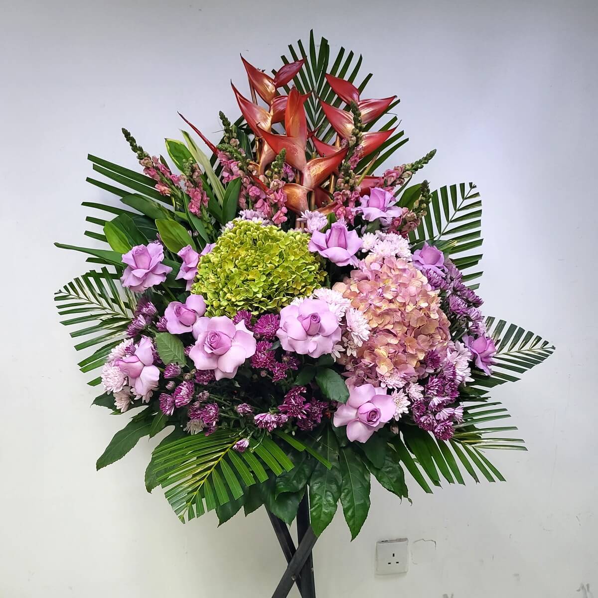 A tropical-style grand opening flower stand with purple roses, green and peach hydrangeas, red heliconia and lush greenery.
紫玫瑰、綠與蜜桃繡球花、紅色天堂鳥花及熱帶葉材構成的開張花牌，氣派大方，喜慶非凡。