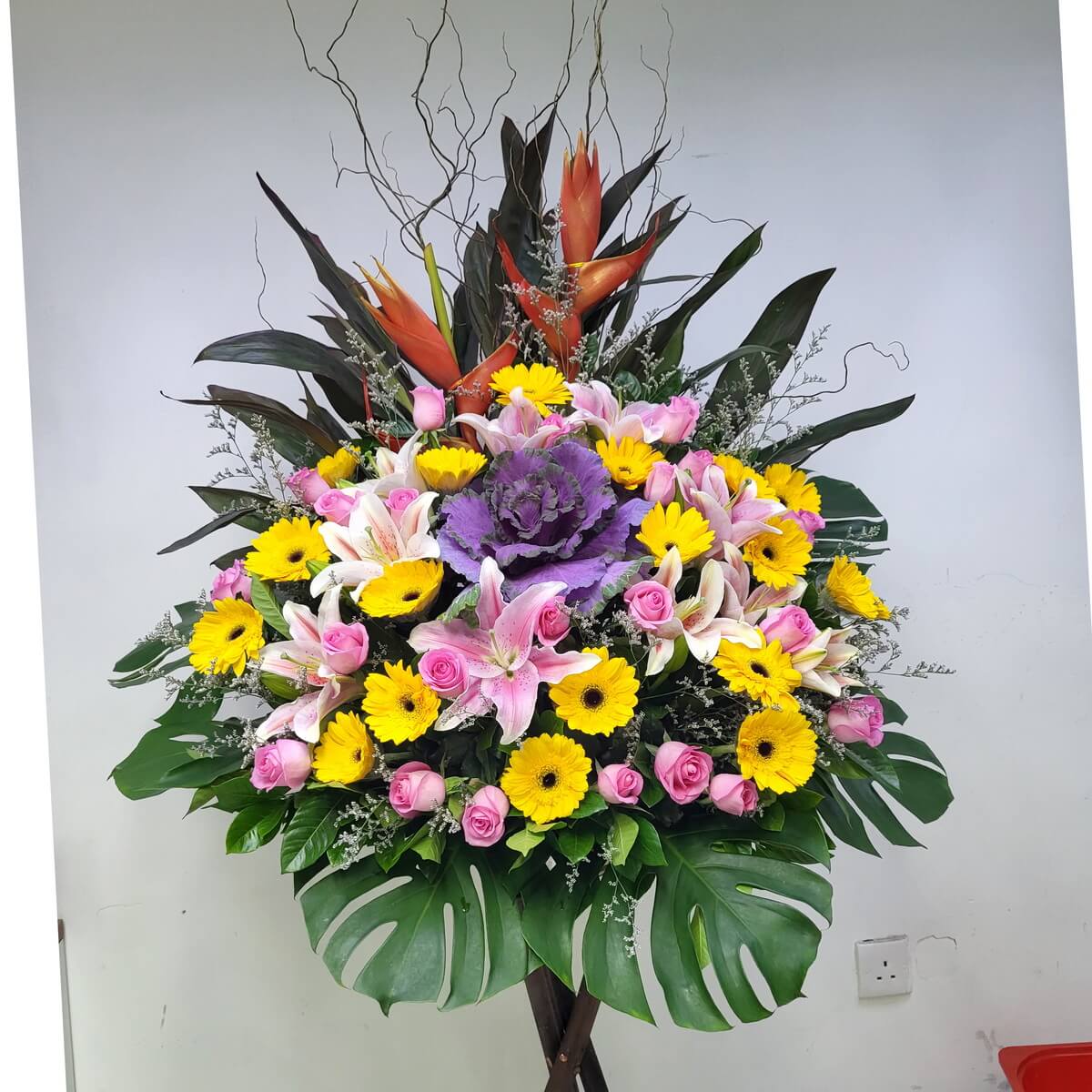 Cheerful grand opening stand featuring yellow gerberas, pink roses, stargazer lilies, and heliconia. 黃太陽花與粉玫瑰交織香水百合與天堂鳥，營造熱烈歡慶氣氛。