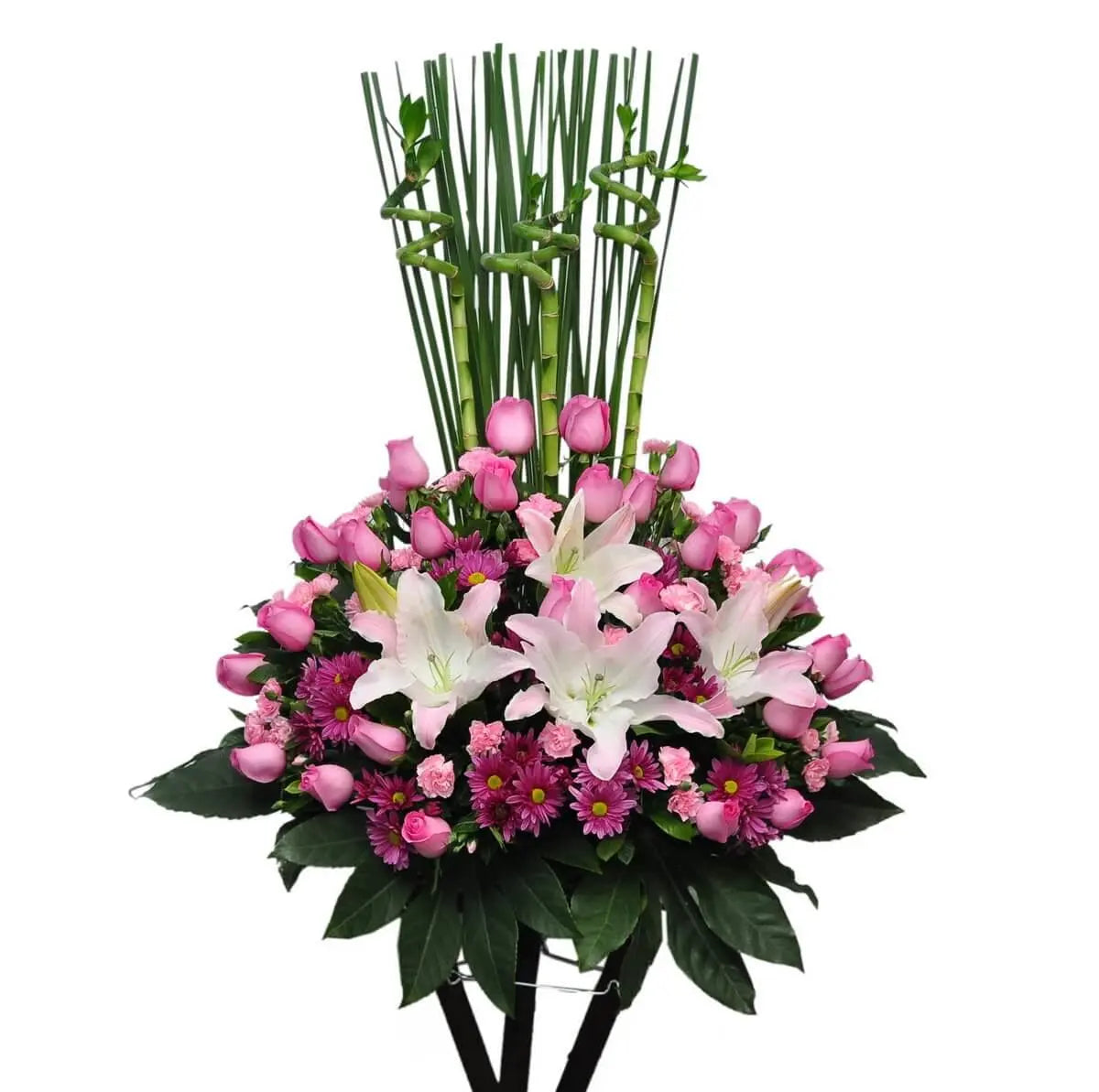 Standing arrangement with white lilies, pink roses, purple chrysanthemums, light pink carnations, and spiral lucky bamboo - 花牌配白百合、粉玫瑰、紫菊、小粉康及螺旋富貴竹，搭配濃密綠葉，造型典雅。