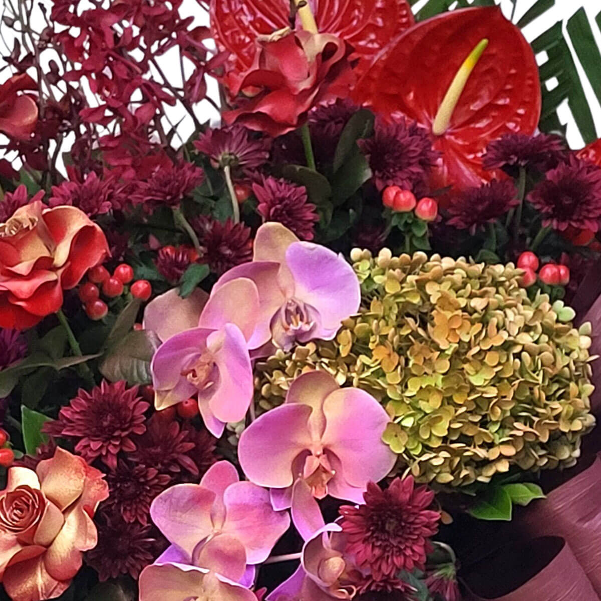 Elegant purple orchids, vintage green hydrangeas, red anthuriums, and burgundy chrysanthemums 絢麗紫蘭、古典綠繡球、紅色火鶴與深紫菊花交織，展現奢華風采。