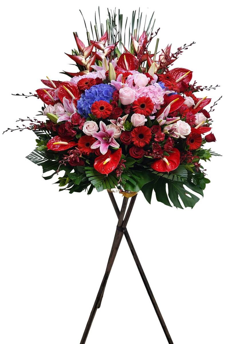 Full standing flower arrangement featuring red anthuriums, stargazer lilies, light pink roses, blue hydrangeas, red gerberas, and orchids - 火鶴花、香水百合、粉玫瑰、藍繡球、太陽花與蘭花的花架設計