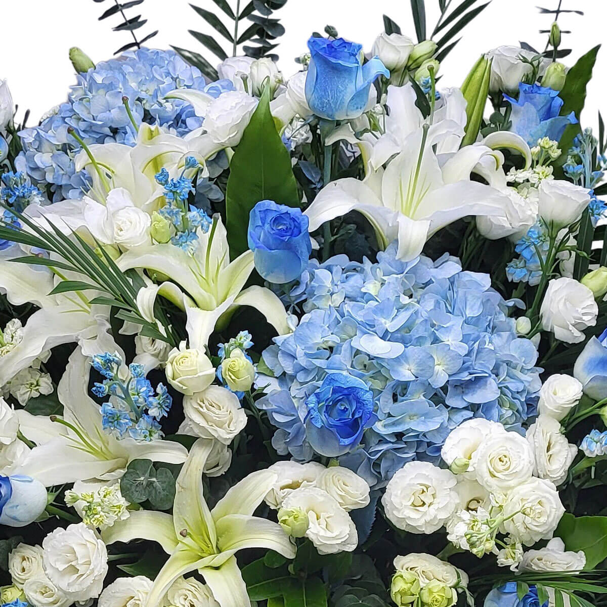 Elegant blue hydrangeas, white lilies, lisianthus, and vivid blue roses blend into a tranquil design 優雅藍繡球、潔白百合、桔梗與藍玫瑰，綻放寧靜之美。