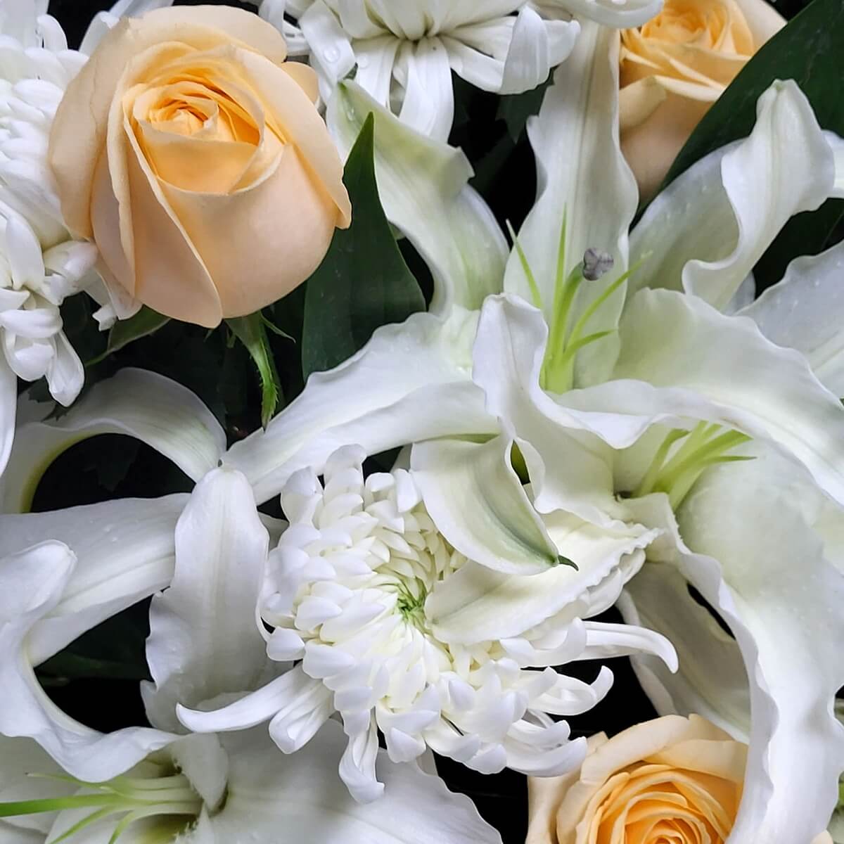 Detail view showing elegant white lilies and curled white chrysanthemums paired with soft peach roses 白百合與彎瓣白菊花細節，襯以柔和蜜桃玫瑰構成優雅搭配