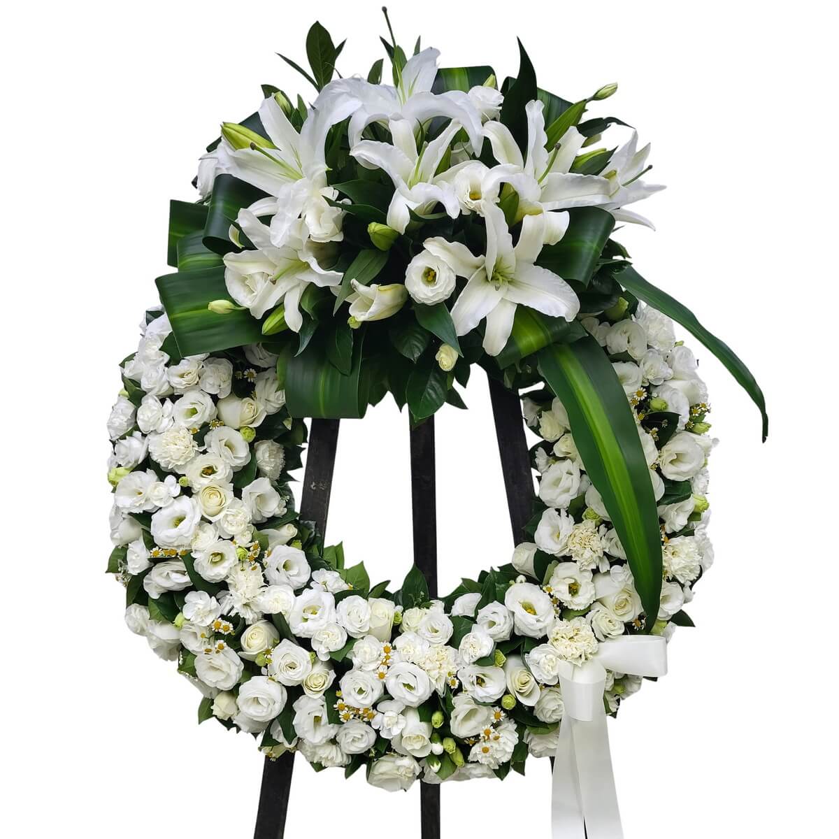 White wreath with tightly packed roses, eustoma, carnations and chamomile across the ring, topped by structured arrangement of open lilies, lily buds and broad overlapping leaves, displayed on a black stand, original photo 白色花圈 玫瑰 洋桔梗 康乃馨 洋甘菊緊密鋪排 頂部百合盛放與花苞並列 配疊片狀綠葉 黑色花架 原相片