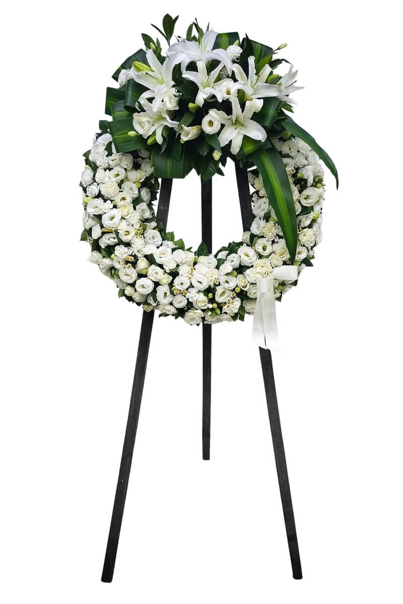 Full floral wreath with top cluster of white lilies, white roses, lisianthus, carnations, chamomile flowers and broad tropical greens, mounted on a black stand - 白百合頂部簇狀設計配玫瑰、洋桔梗、康乃馨、小白菊及寬葉熱帶綠葉花圈連黑色支架展示