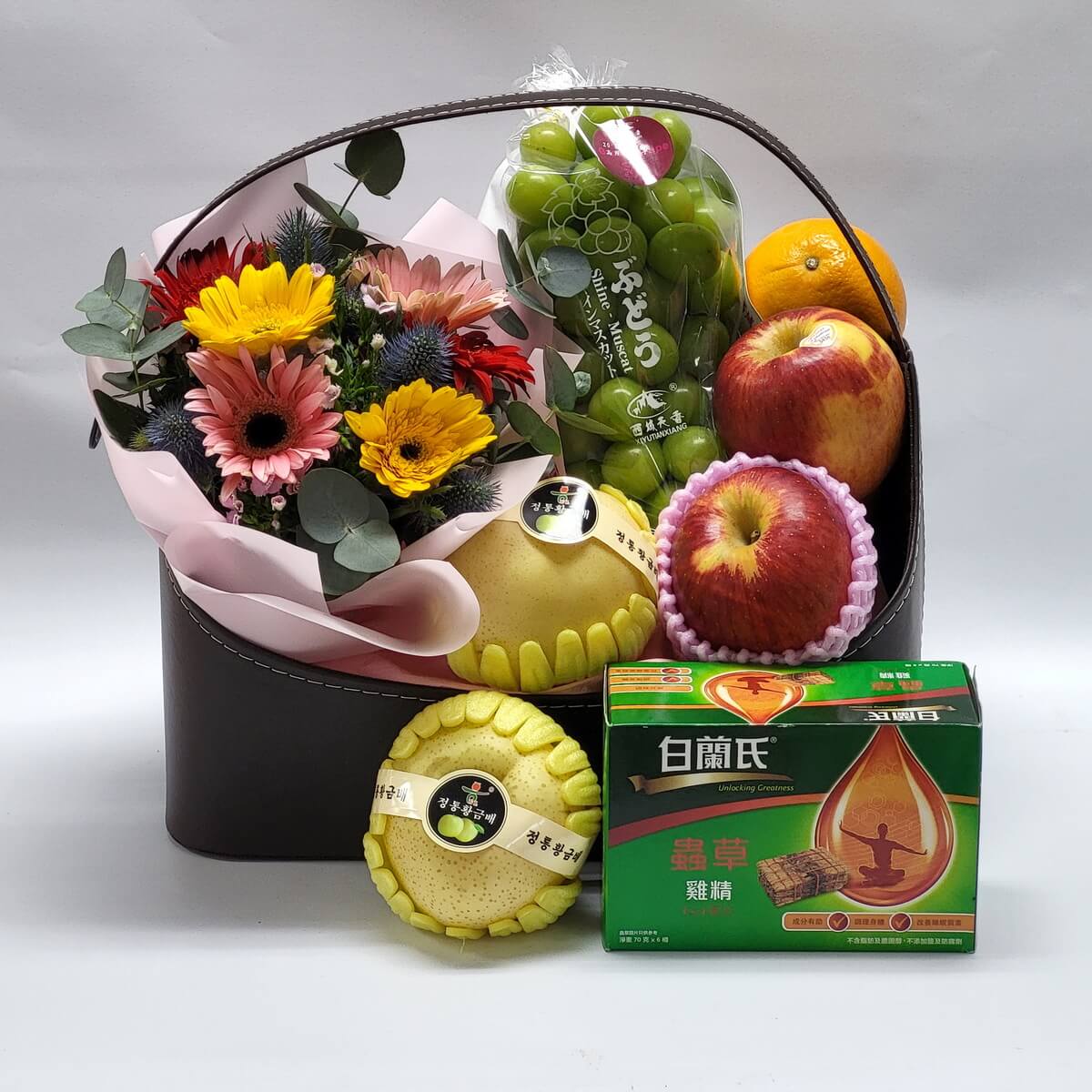A wellness gift basket with fresh flowers, Korean pears, apples, muscat grapes, oranges, and Bai Ling Cordyceps Chicken Essence — ideal for loved ones, elders, or recovery gifts.健康花果禮籃，內含鮮花束、韓國梨、蘋果、青提子、橙及白蘭氏蟲草雞精，滋補養生，適合送給親友、長輩或康復中的摯愛