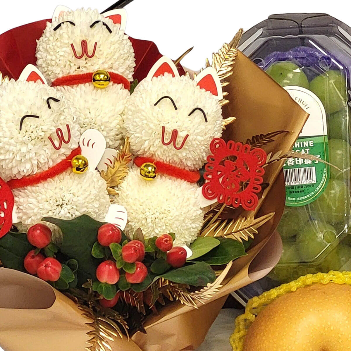 Festive bouquet with three white lucky cats, red berries, and gold leaves, alongside Sunshine Muscat grapes and a pear 花束有三隻白色招財貓，配紅果與金葉，搭送香印提子與水晶梨，送禮大方吉祥。