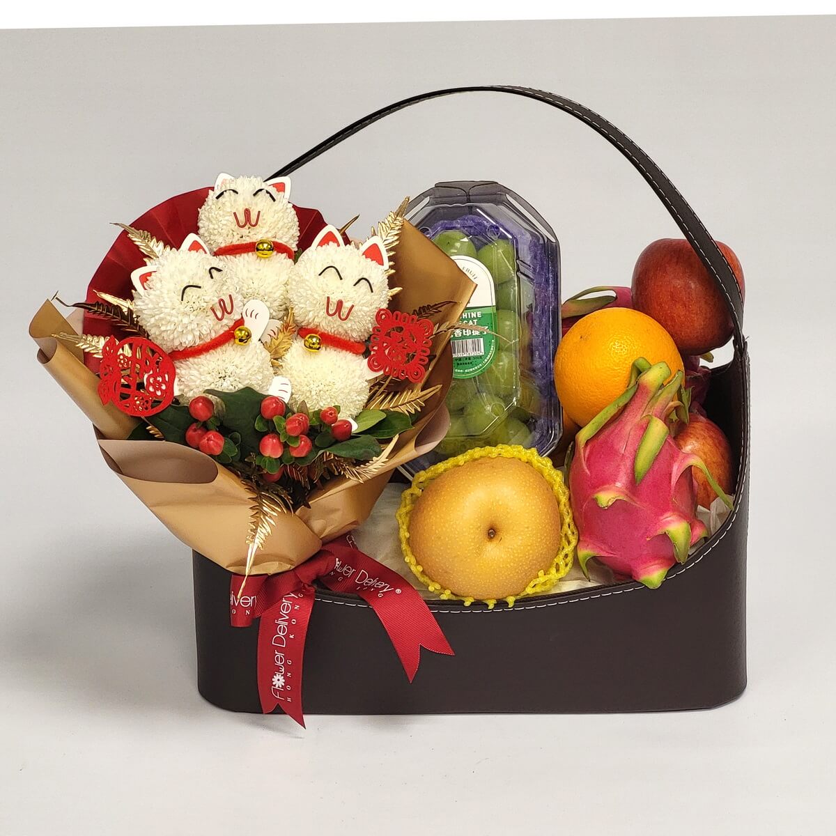 Gift hamper featuring a bouquet of plush lucky cats with festive red accents and a selection of fruits 水果禮籃搭配招財貓布偶花束，內含火龍果、橙子、蘋果、水梨與葡萄，象徵吉祥與健康。