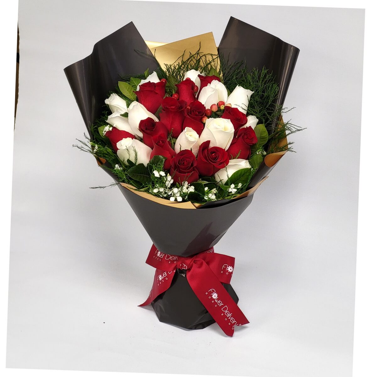 Hand-tied bouquet with red and white roses, filler flowers, berries, and foliage 紅白玫瑰搭配白色碎花、冬青果及綠葉設計，黑色與金色包裝紙包裹，紅色絲帶束口，層次豐富。