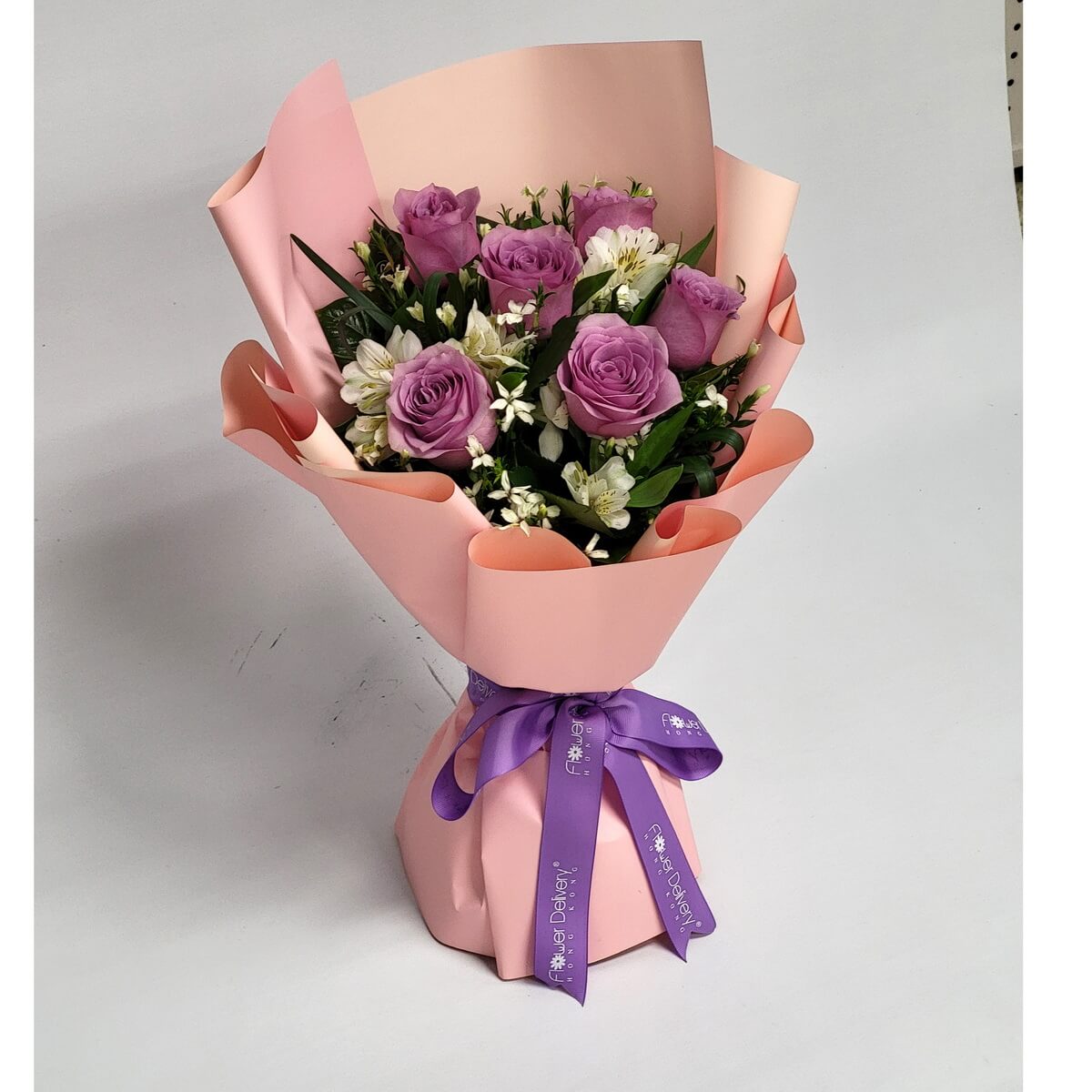 Original bouquet featuring lavender purple roses and white alstroemeria with layered green foliage, hand-tied and finished with soft pink wrapping and ribbon. 紫色玫瑰與白色六出花花束-層次花藝設計與粉色包裝