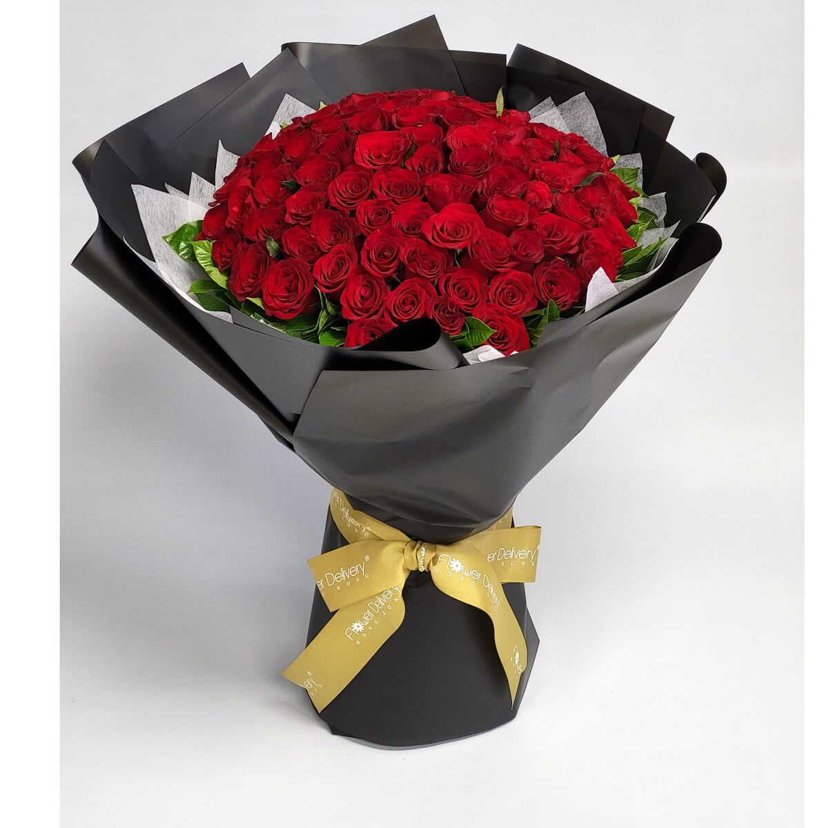 Hand-tied bouquet with a dense dome of red roses and foliage, in black wrapping and gold ribbon 鮮紅玫瑰緊密排列成圓頂造型，配綠葉設計，黑色包裝紙及金色絲帶束口，手綁大型花束風格。