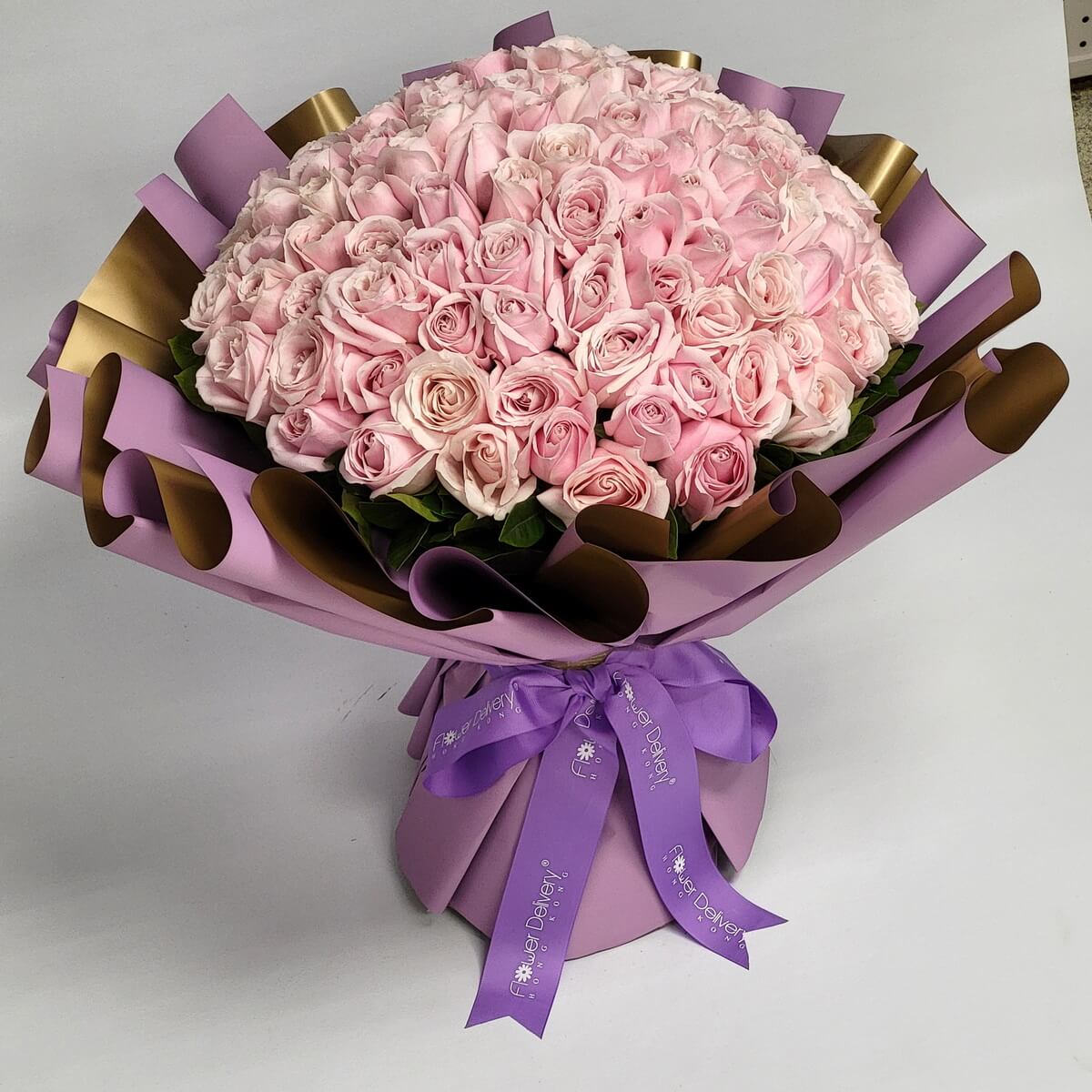 Original photo of a 99-stem blush pink rose bouquet arranged in a dome shape with layered purple and gold wrapping, finished with a purple “Flower Delivery” ribbon - 99枝淺粉紅玫瑰圓形花束，配紫金分層包裝及紫色Flower Delivery絲帶