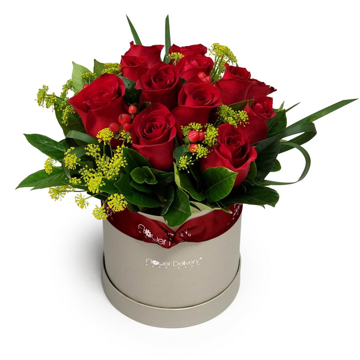 Arrangement of red roses with yellow filler blooms, red berries, and greenery in a beige round box. 紅玫瑰配黃色襯花及紅色果實，綠葉環繞，擺設於米色圓形花盒中。