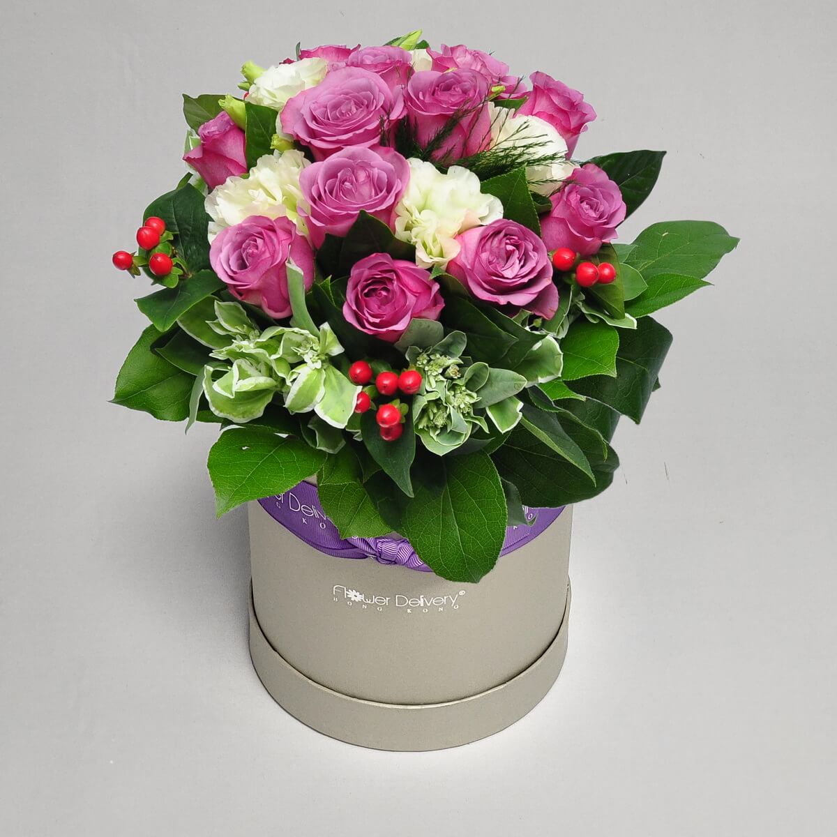 Round flower box featuring purple roses, white lisianthus, red hypericum berries and mixed green foliage with variegated accents - 紫玫瑰、白洋桔梗、紅貫眾果及斑葉混合綠材圓形花盒設計