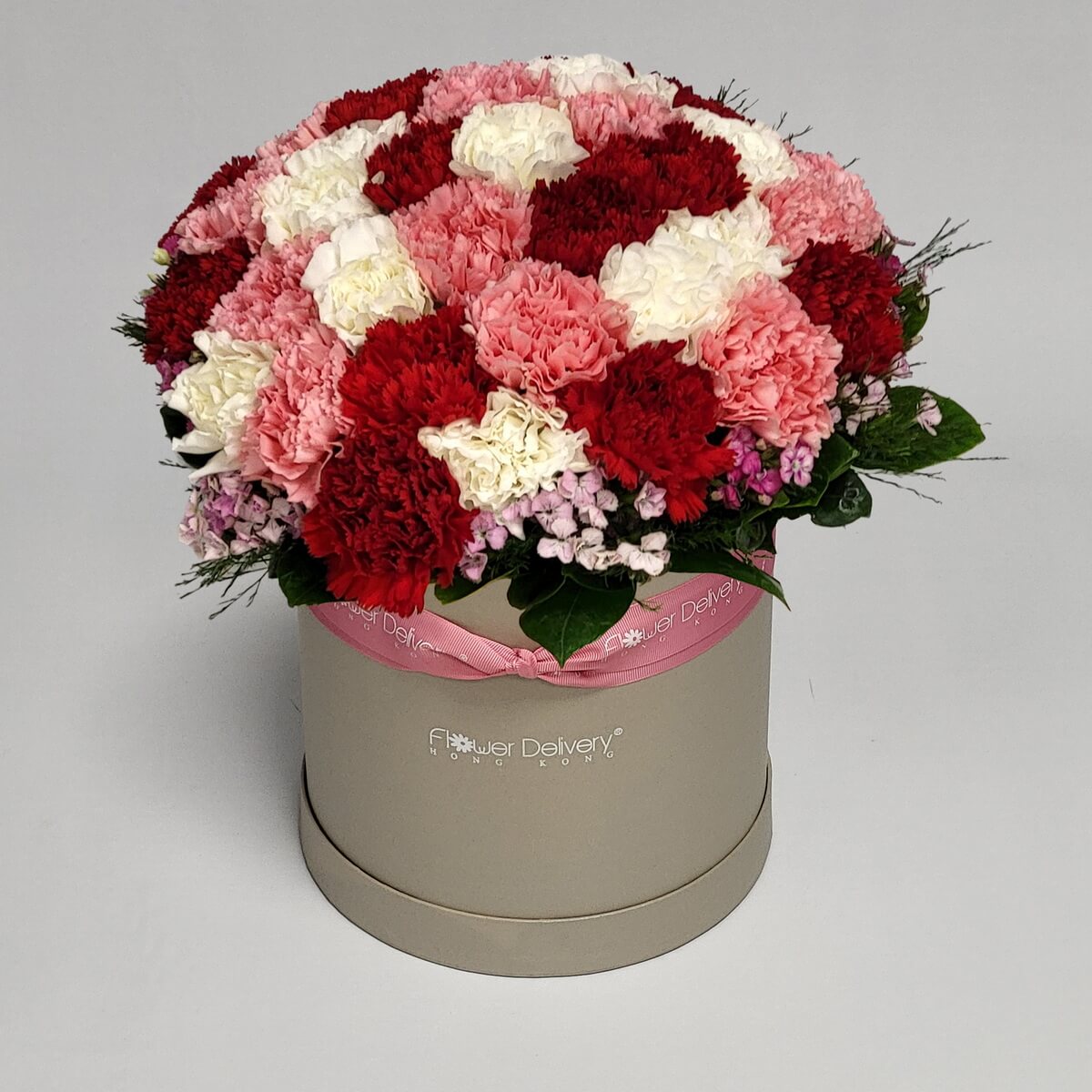 Original photo of round floral box arrangement featuring red, pink and white carnations with pink dianthus and green foliage - 紅色、粉紅及白色康乃馨配石竹及綠葉盒裝花藝設計