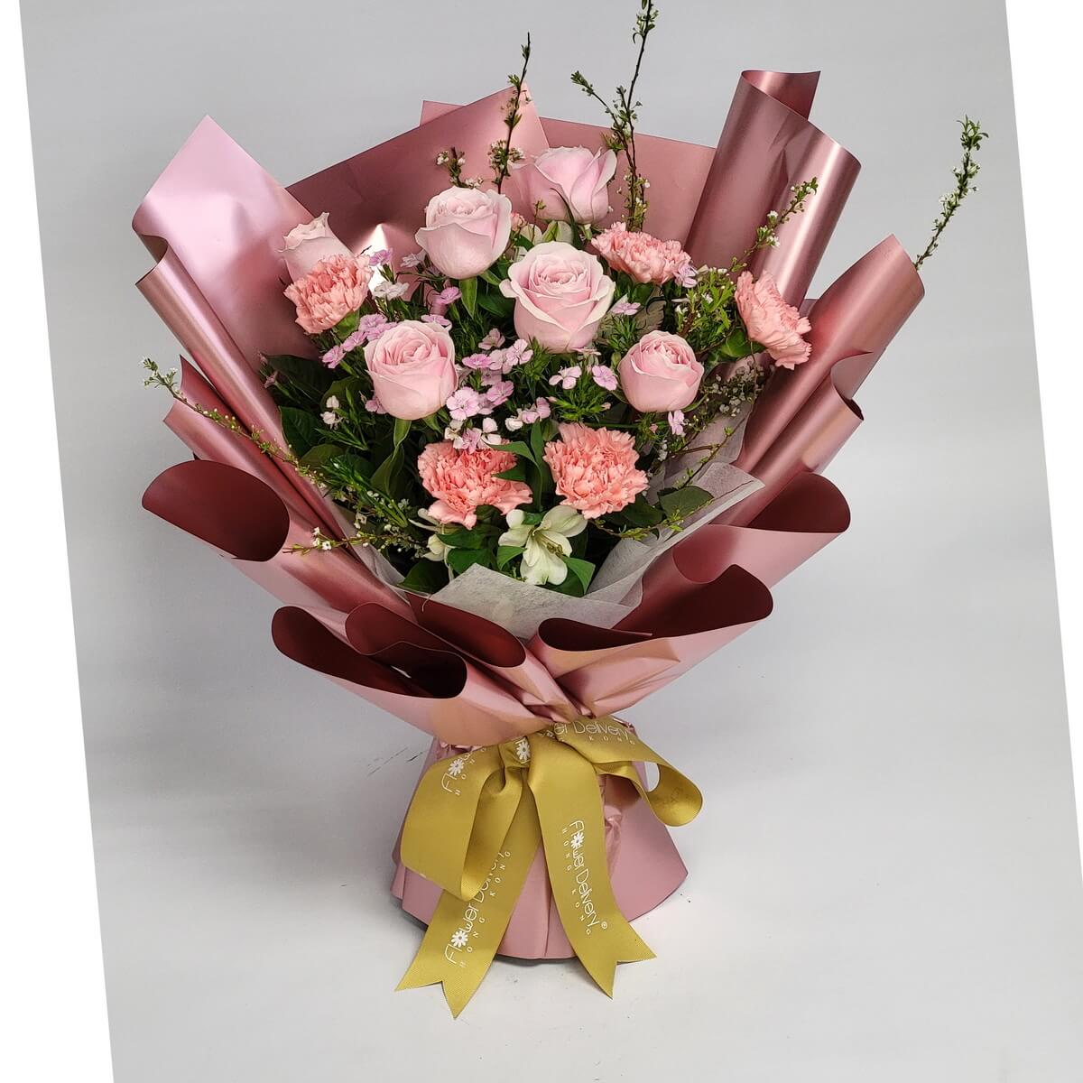 Original photo of a blush pink rose and pink carnation bouquet with soft pink wax flowers, fresh white alstroemeria, and seasonal foliage, wrapped in layered dusty rose metallic paper tied with a gold satin ribbon - 淡粉紅玫瑰及粉紅康乃馨花束原照，配粉紅蠟梅、白色小百合及時令葉材，玫瑰金色層疊包裝紙繫金色緞帶